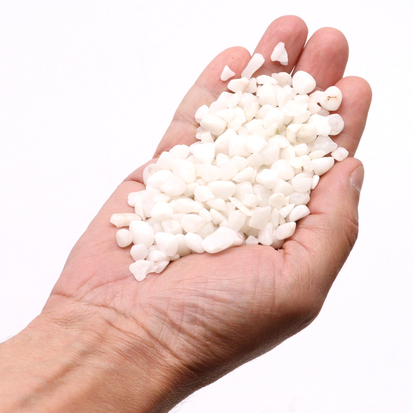 Hand holding polished white quartz gemstone chips from SGI Online for jewelry making and decoration SGI Online