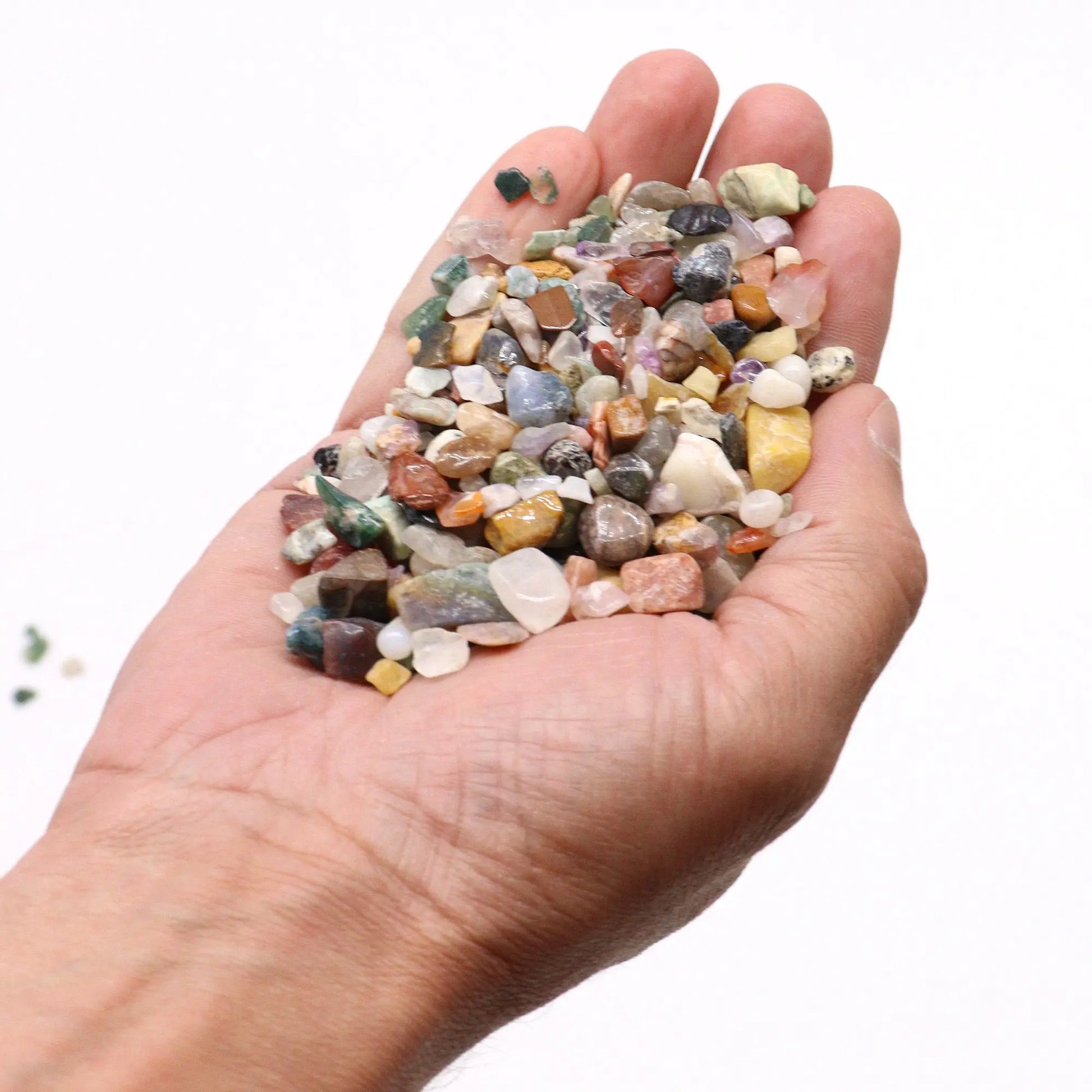 Hand holding polished mixed gemstone crystal chips in various colors and shapes from SGI Online