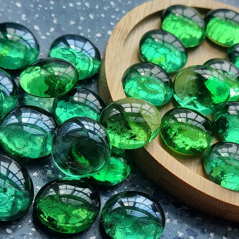 STONED green glass pebbles arranged on a round wooden tray and dark surface background