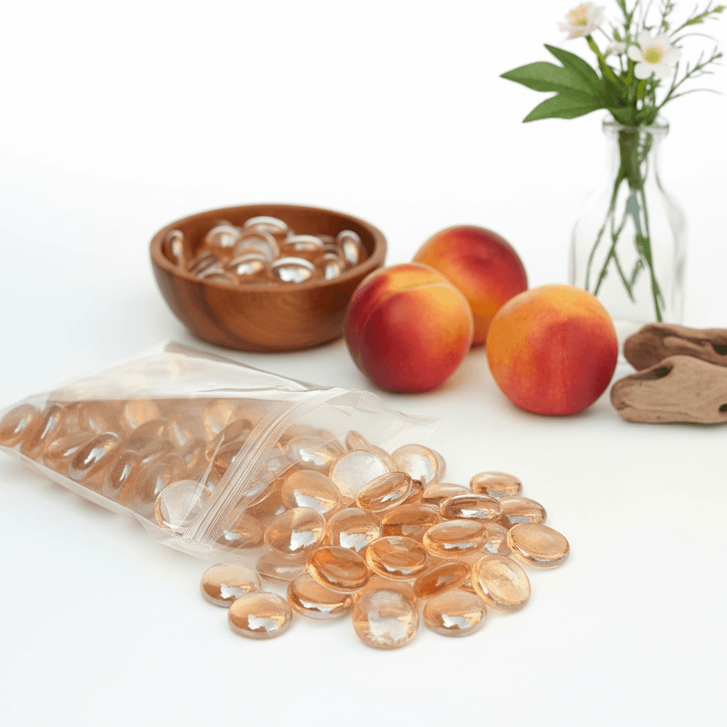 Peach glass pebbles from STONED in a clear bag alongside fresh peaches and a flower vase SGI Online