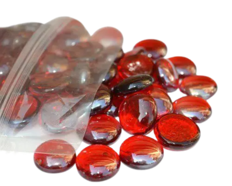 Red glass pebbles spilling out of a clear plastic bag by STONED glass pebbles vendor