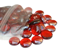 Red glass pebbles spilling out of a clear plastic bag by STONED glass pebbles vendor